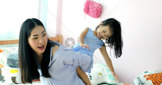 快乐的亚洲小女孩在她母亲的背上在房子里幸福家童年图片