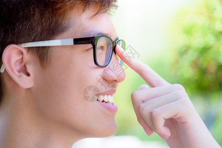 穿着眼镜的亚洲英俊少年男孩肖莱特欢快乐的时装男青年微笑与在泰国绿色自然背景公园的快乐在一起喜悦亚洲青少年男孩笑着随意的灰色树背景图片