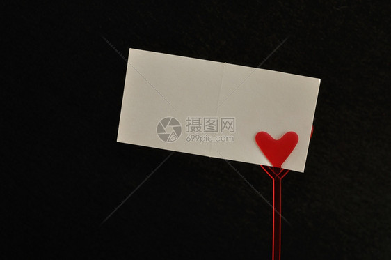 礼物热情一张红心的纸条持有者一张空白卡片在黑色背景下被孤立爱图片