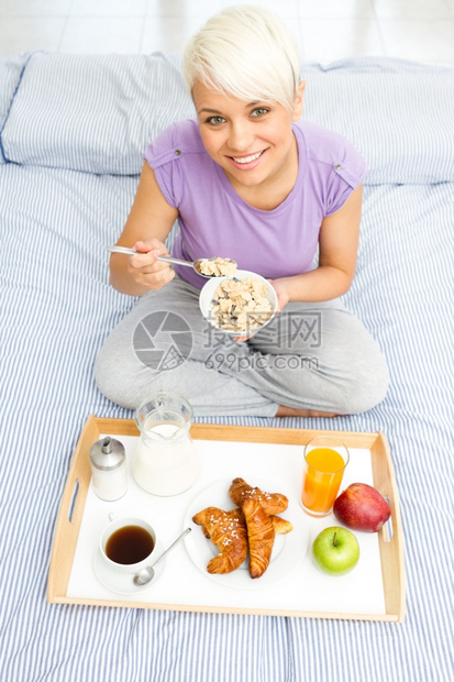 微笑床食物年轻金发女美在卧室吃早餐图片