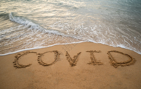 海岸旅行夏天关于沙滩Corona概念的沙和泡沫浪潮手写COVID图片