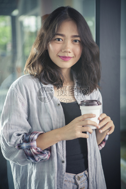 手牵的亚洲女人和热咖啡杯放松情绪微笑着面容观看脸自由职业者图片