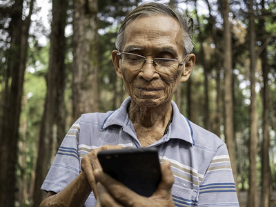 成熟在花园里使用智能手机的亚洲老年男子微笑亚洲人图片