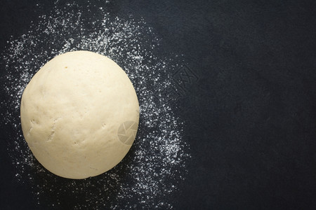 高架在面粉板表的包或披萨上为而举起经证实的酵珠用自然光拍制的选定焦点聚于面粉顶部发酵的证明图片