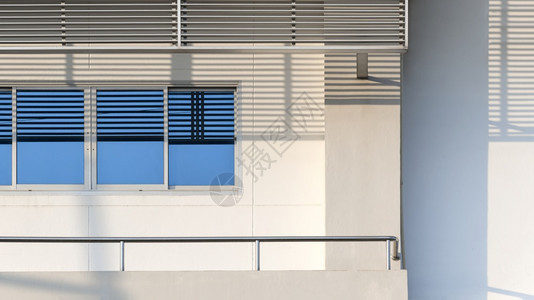 玻璃窗表面的蓝色天空反射不锈钢套和在现代白色办公大楼阳台栏杆上安装不锈钢外部的住宅阳光图片