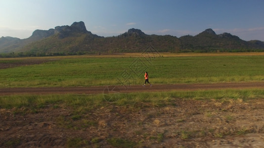 一种山区日落时妇女在农村公路上运行的空中景象马拉松图片