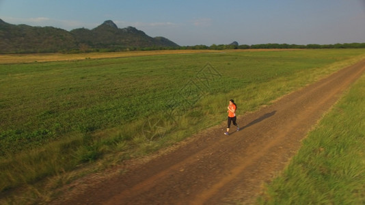 山区日落时妇女在农村公路上运行的空中景象踪迹锻炼女士图片