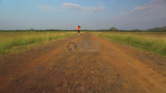 合身女天空山区日落时妇女在农村公路上运行的空中景象图片