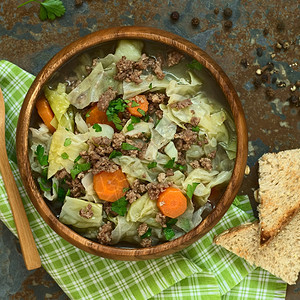 烹饪草本植物碎肉Savoycobbage胡萝卜土豆和小熟食炖菜或木碗里有面纱的浓汤用自然光照板上的片拍摄图片