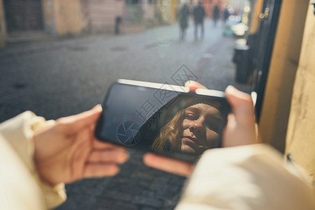 有视频电话的年轻女子通过远程交谈拍摄自相照片手持智能机在屏幕上出现面孔社会的自拍保持图片