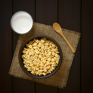 香味早餐在生锈的碗里吃麦片加牛奶杯和侧边木勺子用自然光照着黑木头星制的玻璃图片