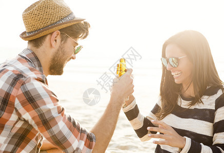 拉丁假期饮料在海滩上玩乐笑和喝啤酒的年轻夫妇图片