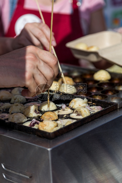 人们棕色的可口用人手在街头食物中烹饪热辣的Takoyaki球图片