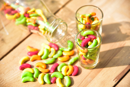 一罐装满彩色糖果的玻璃罐放在木本底桌子颜色对待图片