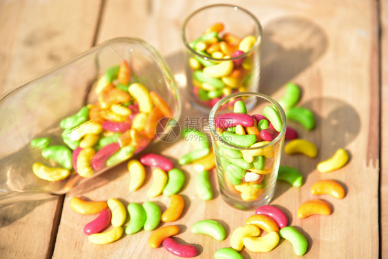 明亮的颜色可口一罐装满彩色糖果的玻璃罐放在木本底图片