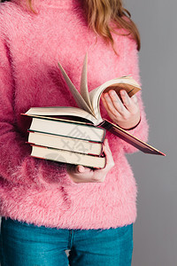 一种身穿粉红色毛衣和蓝牛仔裤垂直照片的少女孩持有几本书图馆图片