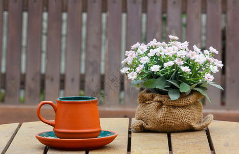 锅勺子喝木制桌上的一小杯咖啡和鲜花背面有木椅放在杯子上的焦点图片