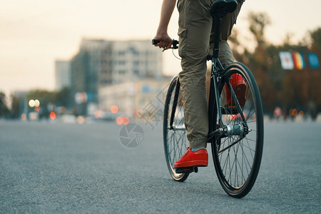 成人车把穿着红色运动鞋和舒适裤子的休闲男腿在城市灰色道路上骑经典自行车的特写复制空间在城市道路上骑经典自行车的休闲男子腿特写健康图片