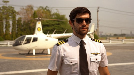 常设在小型私人直升机附近站立着身穿制服的商业飞行员肖像车辆职业图片