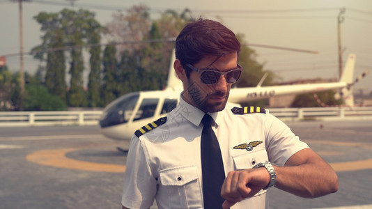 运输门户14在小型私人直升机附近站立着身穿制服的商业飞行员肖像男人图片