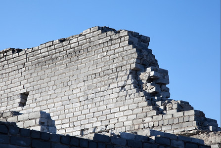 风化岩石废墟由灰砖制成的废墙壁对着蓝天图片