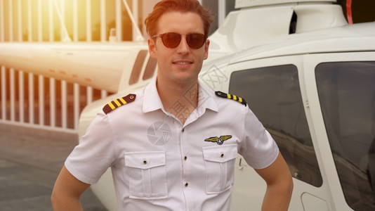 队长航班专业的在小型私人直升机附近站立着身穿制服的商业飞行员肖像图片