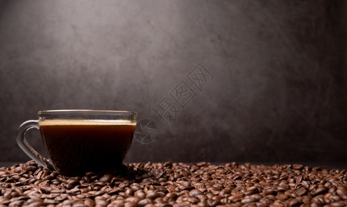 一个咖啡杯和组黑豆的侧面是背景粗黑色咖啡底部纹理以及咖啡底部有质感的美食黑暗图片
