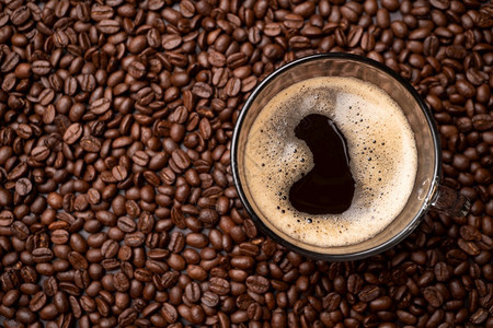 照片咖啡杯和黑豆组的顶端视图是背景粗黑色咖啡底部纹理咖啡底部有质感的新鲜图片