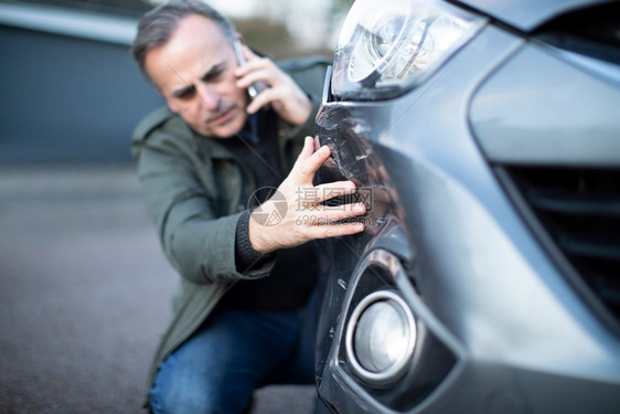 白种人事故凹陷的意外用手机打电话给保险公司后汽车受损的不开心成熟男司机图片