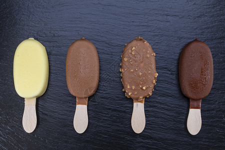 棕色的新鲜冰淇淋贴在木棍上黑石板的巧克力覆盖着冰淇淋粘在黑石板上的巧克力寒冷图片