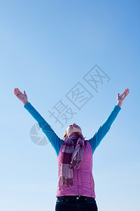热情的蓝色喜悦少女与举起的手站在蓝天对面图片