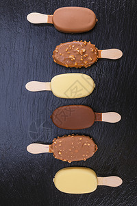 黑石板上涂着巧克力的冰淇淋贴在棍子上的冰淇淋小吃奶油结石图片
