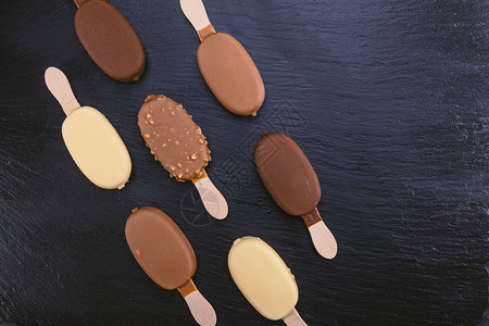 黑石板上涂着巧克力的冰淇淋贴在棍子上的冰淇淋白色自制最佳图片