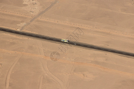 美丽的沥青从飞机窗口查看在沙漠途中沿公路行驶的共汽车鸟瞰沙漠公路旅行冒险公路穿越沙地鸟瞰漠旅行冒险巷道图片
