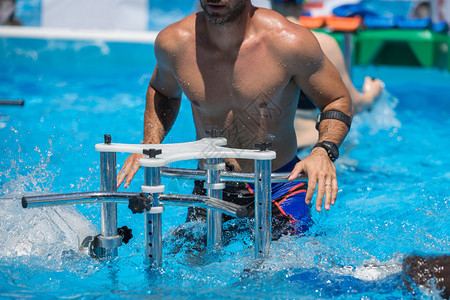 游泳的身体男人孩在室外游泳池里用金属健身器材做水中有氧运动男孩在室外游泳池里用金属健身器材做水中有氧运动图片