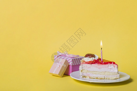 花朵最佳黄色背景下带两个礼盒的发光蜡烛切片蛋糕分辨率和高品质精美照片黄色背景下带两个礼盒的发光蜡烛切片蛋糕高品质精美照片概念维他图片