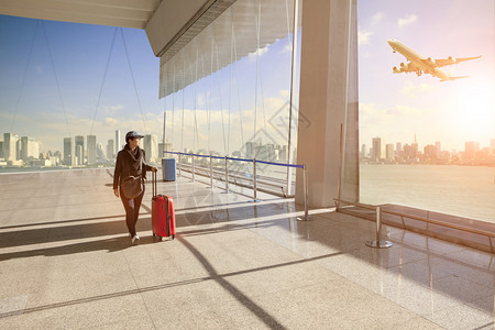 在机场候楼和客上行走的携带随身李巡回妇女乘坐客机飞越城市大楼归属感单身的城市图片