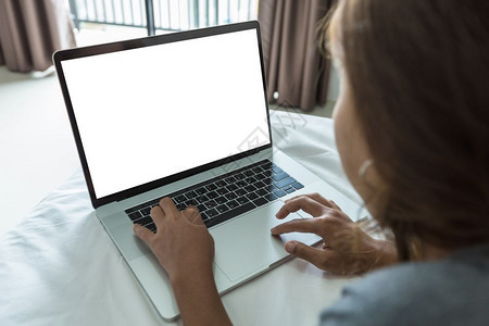 背部沟通打字妇女在房间里的床上打手提笔记本电脑键盘白屏幕图片