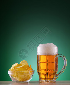 麦酒一种张绿色背景的白啤酒和泡沫及薯片脸杯一带有泡沫及碎屑的轻啤酒脸杯吧图片