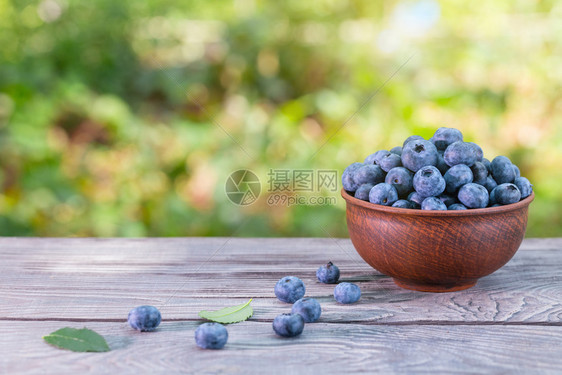 蓝莓在木制桌边的粘土碗中蓝莓绿色天然背景夏季保持生命自然产品和收获概念在木制桌子上的粘土碗中蓝莓健康抗氧化剂植物图片