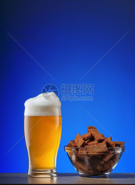 马克杯酒吧桌子一带泡沫的淡啤酒和蓝色背景上的一盘饼干杯带泡沫的淡啤酒和蓝色背景上的一盘饼干图片