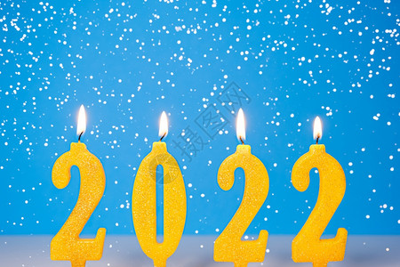 燃烧黄色蜡烛的假日背景20年快乐新概念燃烧黄色和金蜡烛蓝背景与落雪隔离新年快乐概念蜡烛蓝色背景与落雪明亮的假期金背景图片