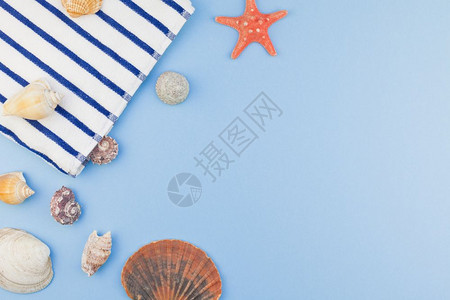 最小的颜色海滩毛巾和贝壳及星的顶端视图以面糊蓝底色背景影印空间极小文字模板版样的形式呈现在浅滩毛巾海壳和星上水背景图片