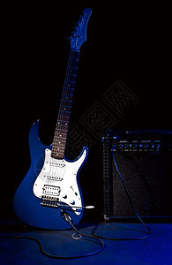 脖子优质的黑色背景蓝光射线中的电动吉他和组合放大器颤音图片