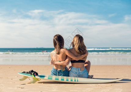 坐在沙滩上两个冲浪爱好者图片