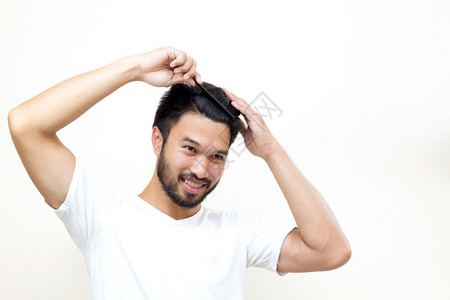 西班牙裔关心人的概念微笑的年轻男子用白色背景梳头发都市型男图片