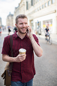 手机男人在城市街上漫步谈论移动电话喝服装图片