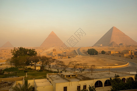 古老的埃及吉萨日落时金字塔大历史的骆驼背景图片