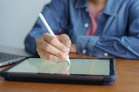 流动药片屏幕工作妇女的和在平板电脑上写作在木桌布背景上有笔记本电脑图片