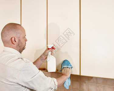 家庭工作一名男子使用清洁布和洗涤剂喷雾他打扫厨房橱柜门像家一样粗短的男人图片